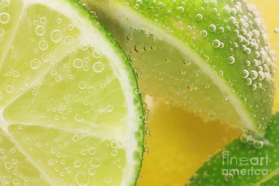 Lemon and lime slices in water Photograph by Simon Bratt