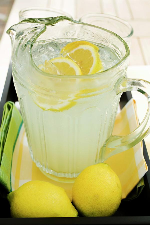 Lemonade In A Glass Jug With Slices Of Lemon And Ice Photograph by ...