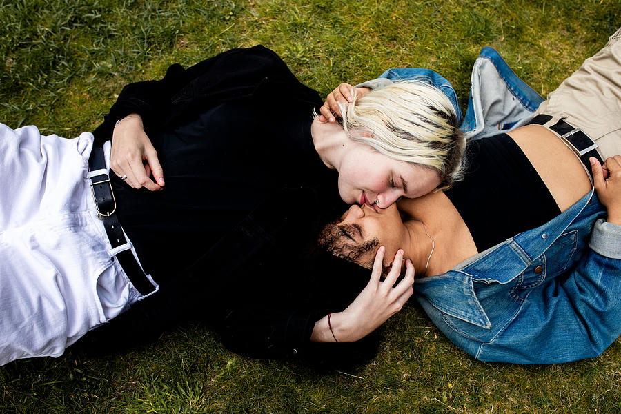 LGBT couple lying in the grass kissing Photograph by Sophie Mayanne