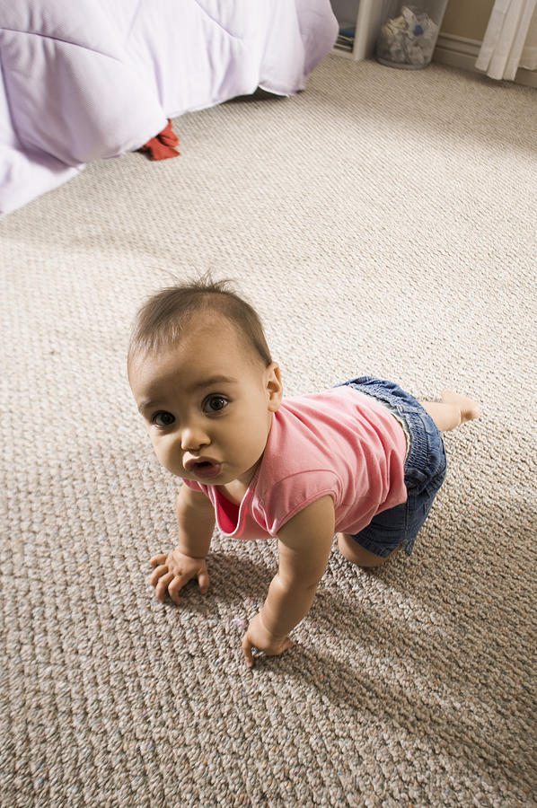 Lifestyle Shot Of A Female Toddler In A Pink Shirt As She Crawls And Looks Up At The Camera Photograph by Photodisc