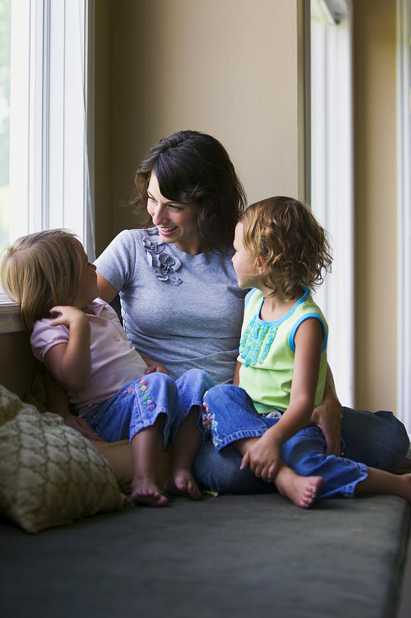 Lifestyle Shot Of A Mother As She Sits On A Couch By The Window With Her Two Children Photograph by Photodisc