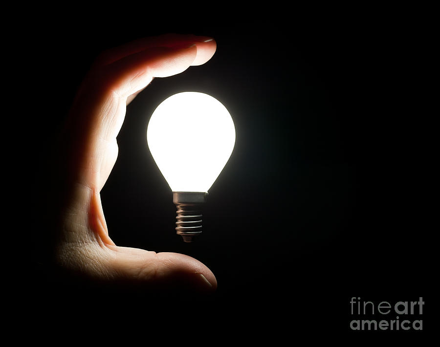 Light bulb and hand Photograph by Simon Bratt
