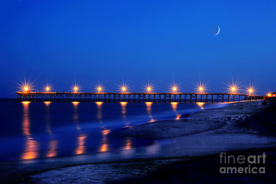 Lighted pier on ocean in evening by Dan Friend Lighted pier on ocean in evening by Dan Friend