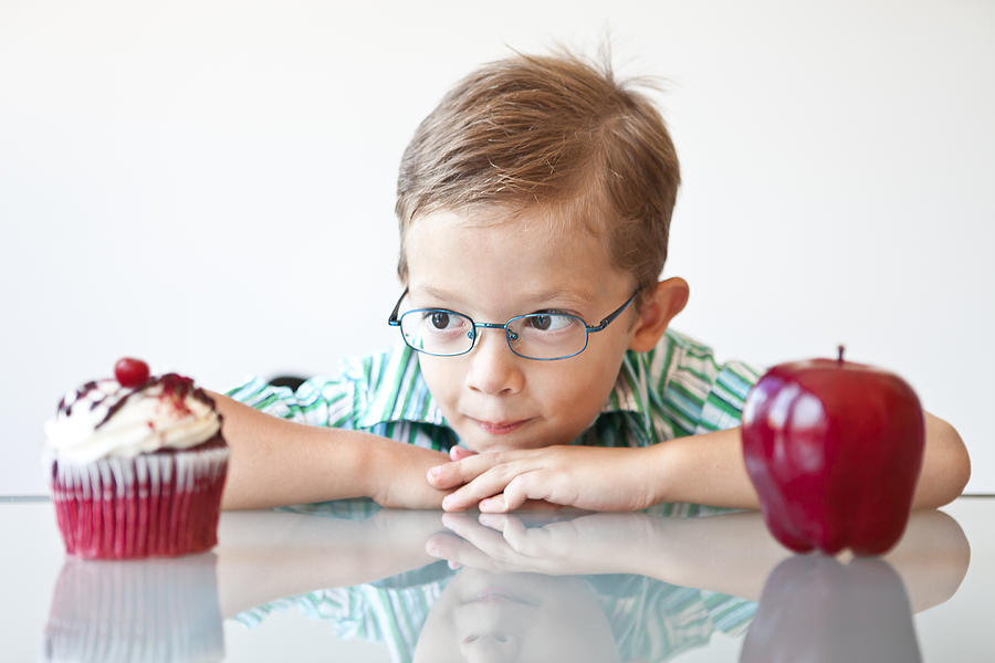 Little boy choosing between a cupcake and apple Photograph by Diane39