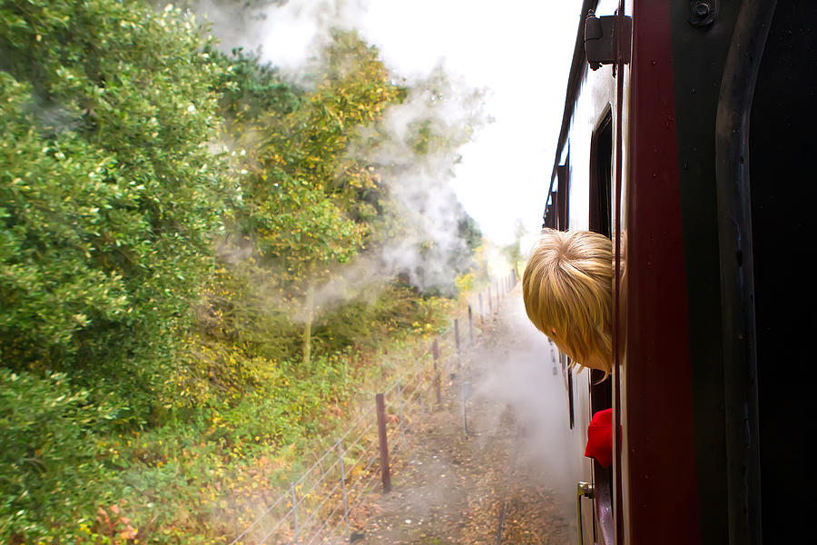 Young man looking out of train window on the historic steam engine