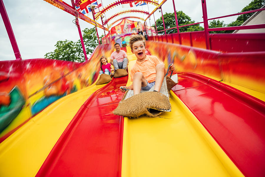 Little boy on Slide at a Funfair Photograph by SolStock