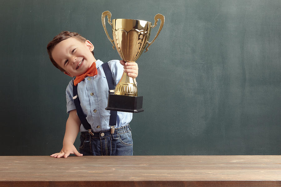 Little boy raising a golden trophy Photograph by Pinstock