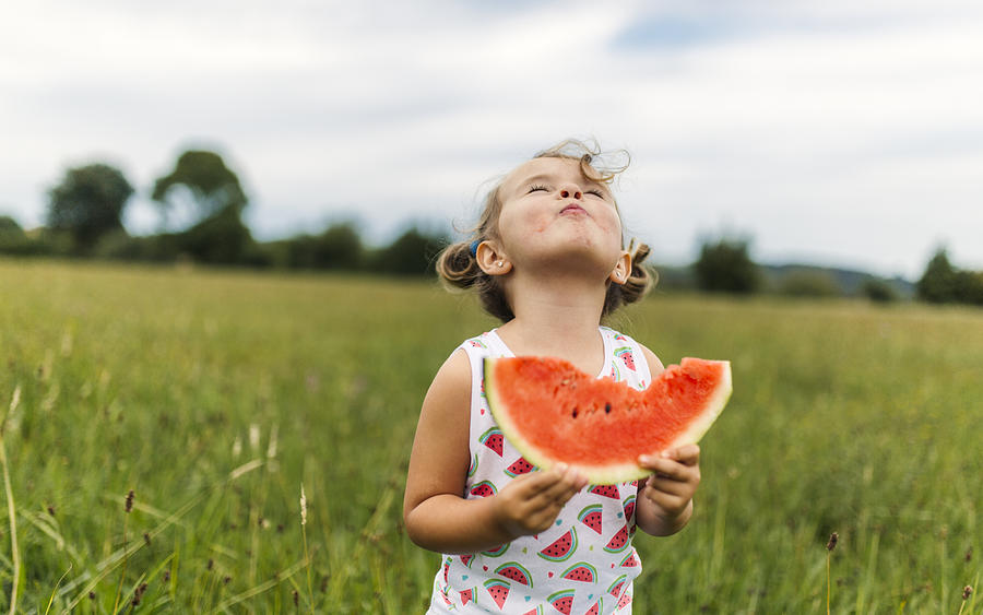 Little girl eating watermelon on a meadow Photograph by Westend61