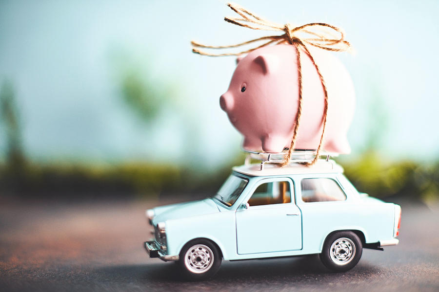 Little pink piggy bank tied to the top of an old car Photograph by CatLane