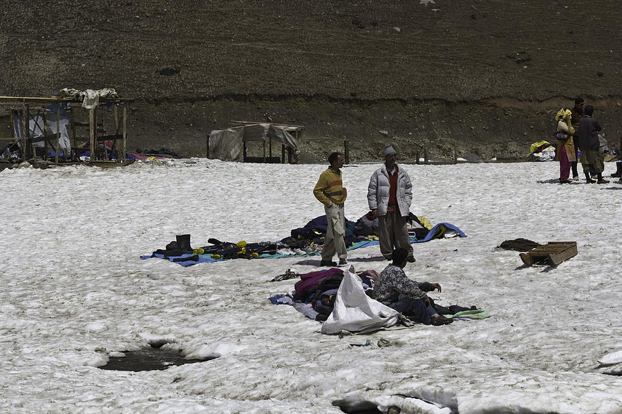Locals with a pile of ice boots and snow jackets amidst the snow Photograph by Ashish Agarwal