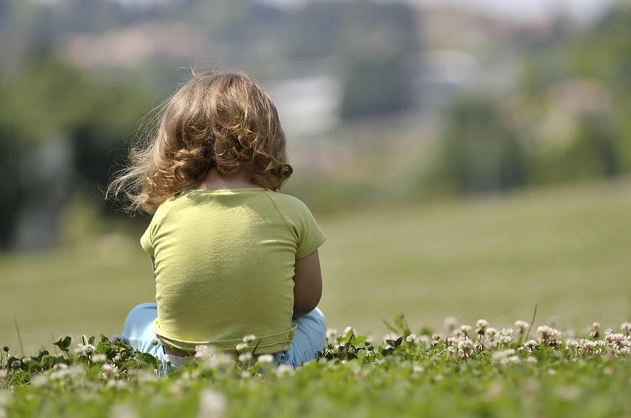Lone child sitting in field of flowers Photograph by Abeleao