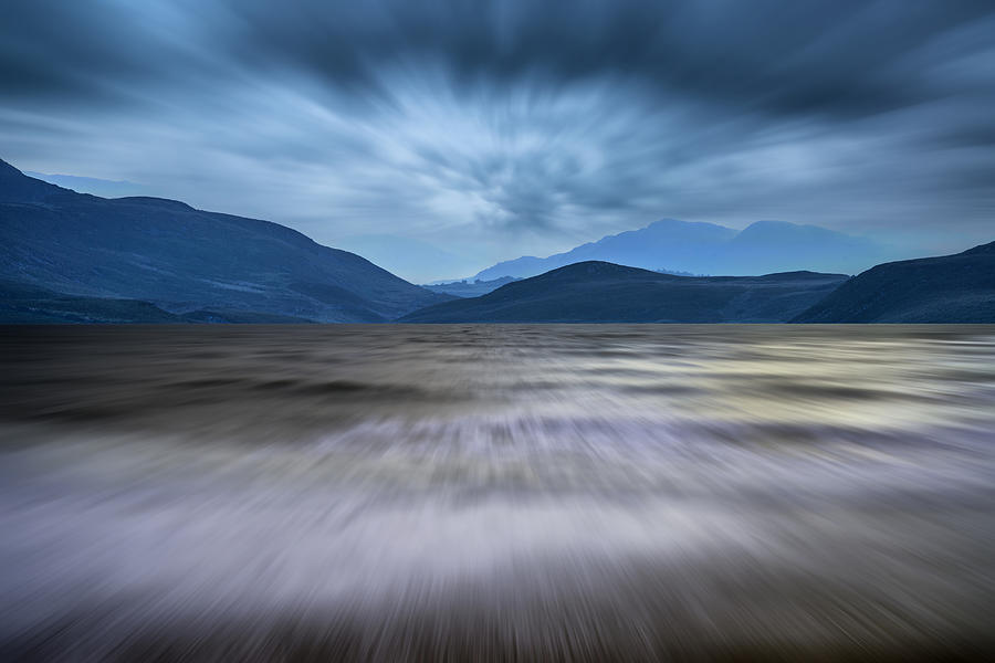Landscape Photograph - Long exposure landscape of stormy sky and mountains  over lake by Matthew Gibson