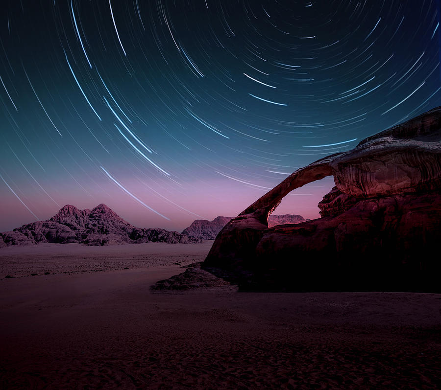 Long exposure of the stars in the Wadi Rum desert of Jordan with natural arch. Photograph by Artur Debat