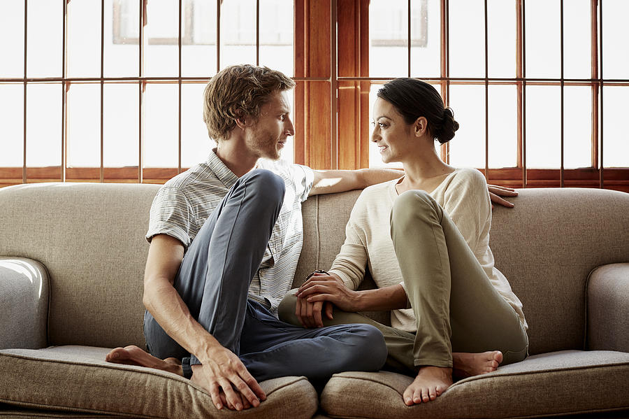 Loving couple siting on sofa at home Photograph by Morsa Images