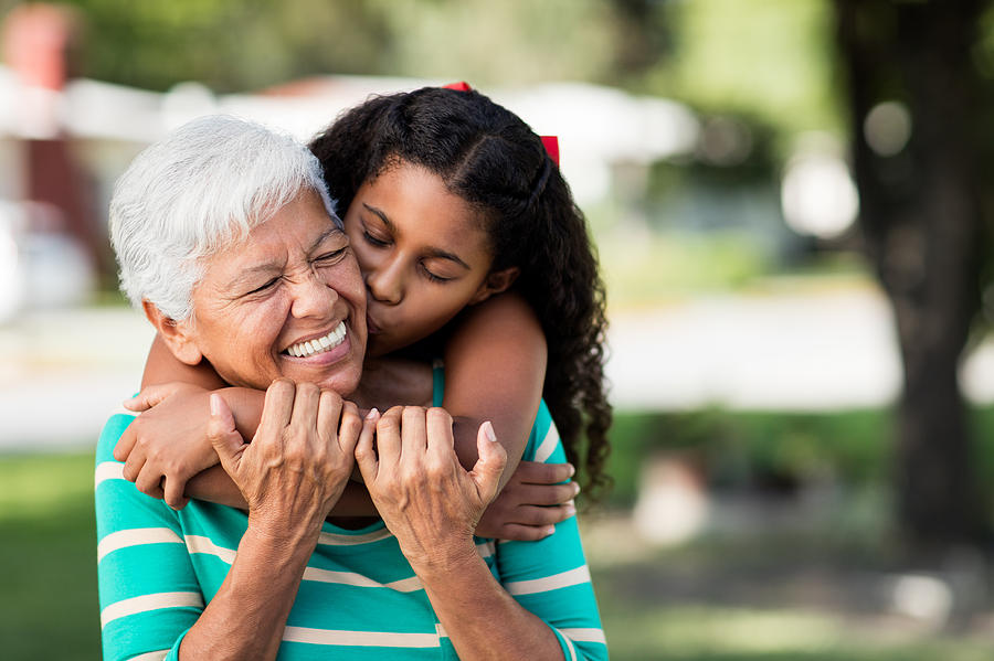 Loving teen girl embracing and kissing grandmother Photograph by Aldomurillo