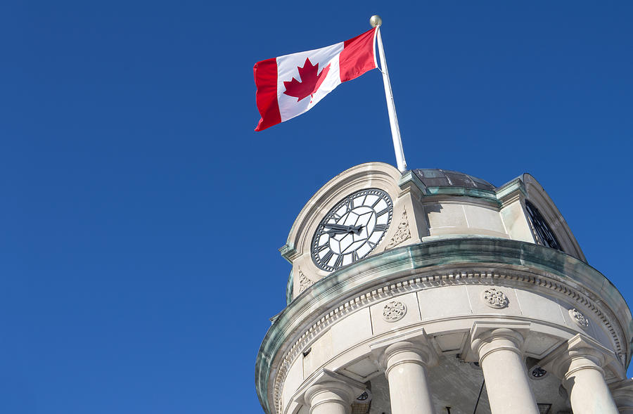 Low angle view of a Canadian flag flying on a clock tower Photograph by SimplyCreativePhotography