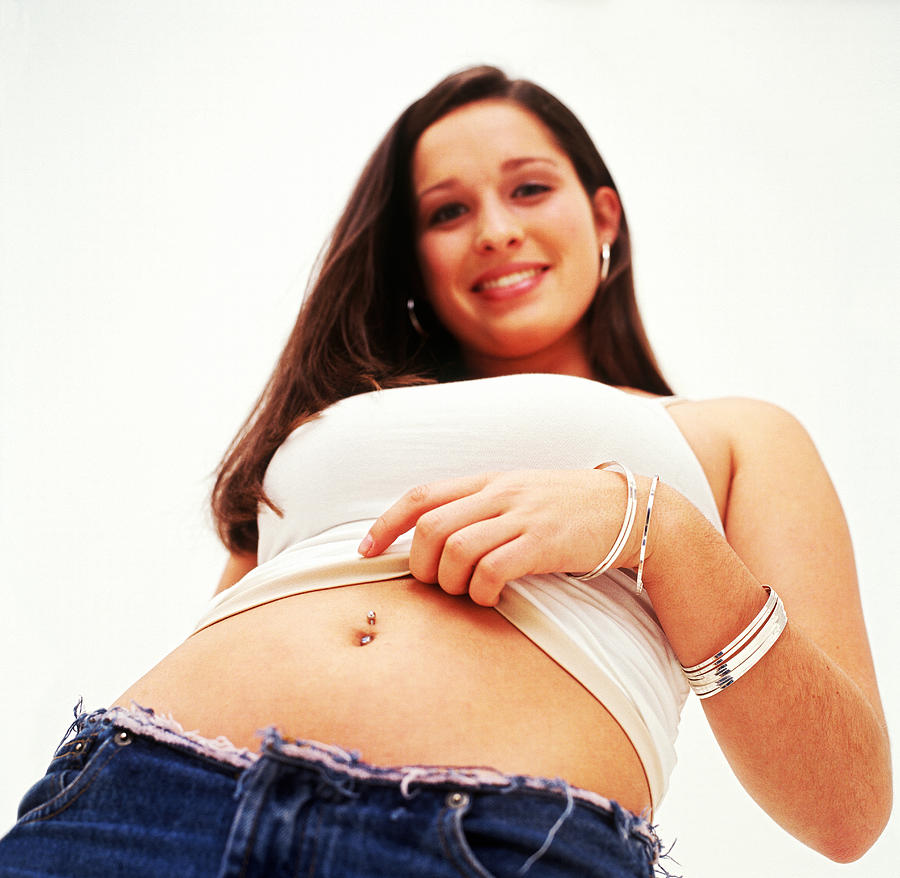 Low Angle View Of A Teenage Girl Showing Her Belly Button Ring Photograph by Stockbyte