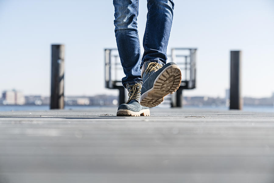 Low section of man walking on pier on sunny day in Germany. Photograph by Tina Terras & Michael Walter
