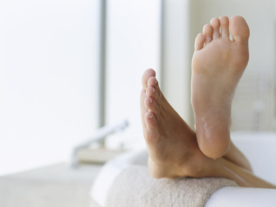Low Section View Of A Persons Feet Resting On The Edge Of A Bathtub Photograph by Stockbyte