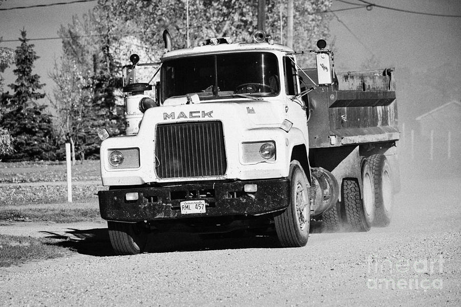 Truck Photograph - mack truck driving down rough unpaved rural road in farming community Saskatchewan Canada by Joe Fox