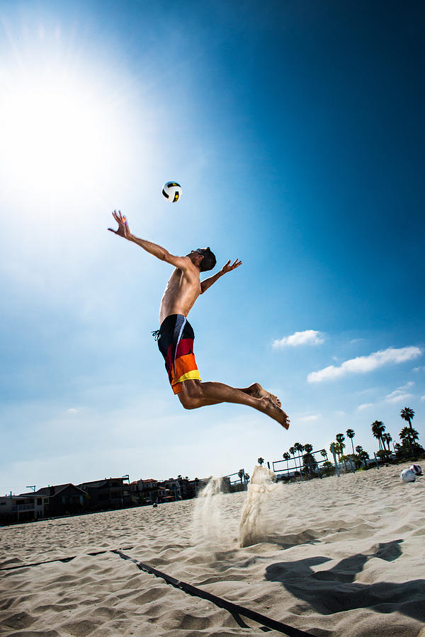Male beach volleyball player jumping mid air to hit ball Photograph by Corey Jenkins