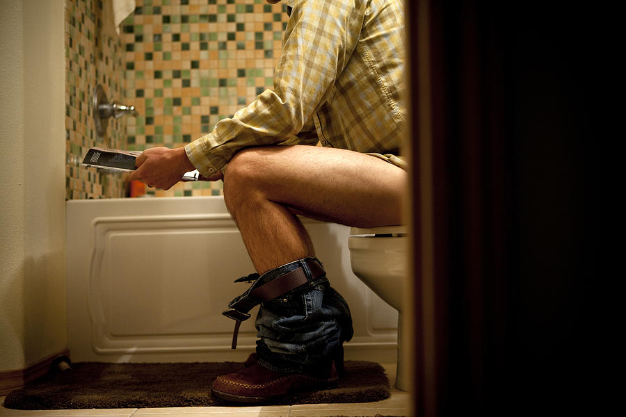 Male reading magazine on toilet. Photograph by Jordan Siemens