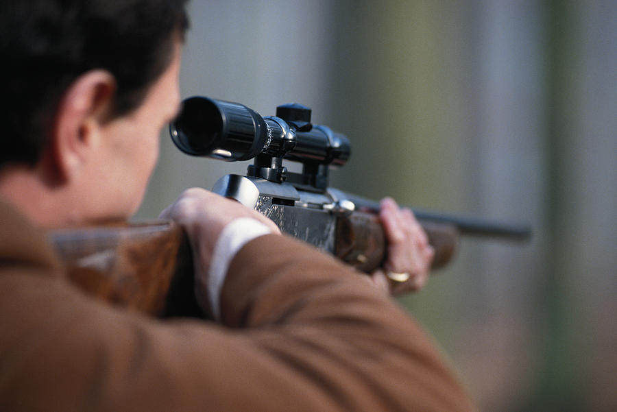 Man aiming rifle, close-up, rear view Photograph by David De Lossy