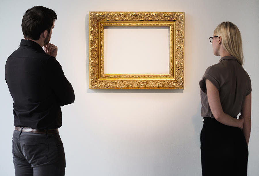 Man and woman looking at empty picture frame Photograph by Tetra Images