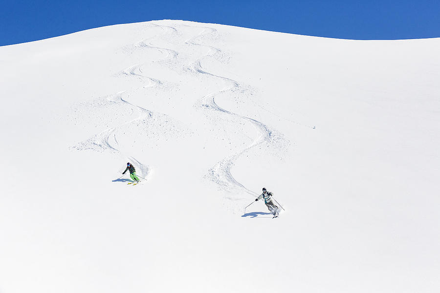 Man and woman skiing down mountain Photograph by Aluxum