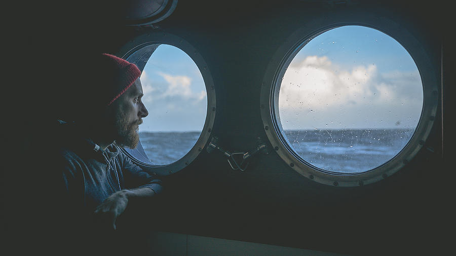 Man at the porthole window of a vessel in a rough sea Photograph by Piola666