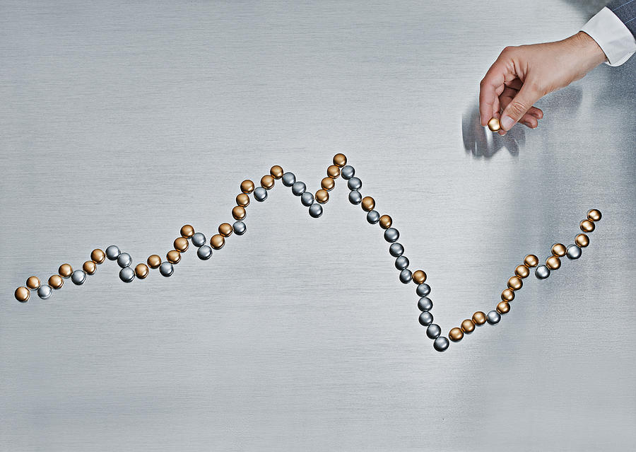 Man constructing a line graph with silver pieces. Photograph by Pulse