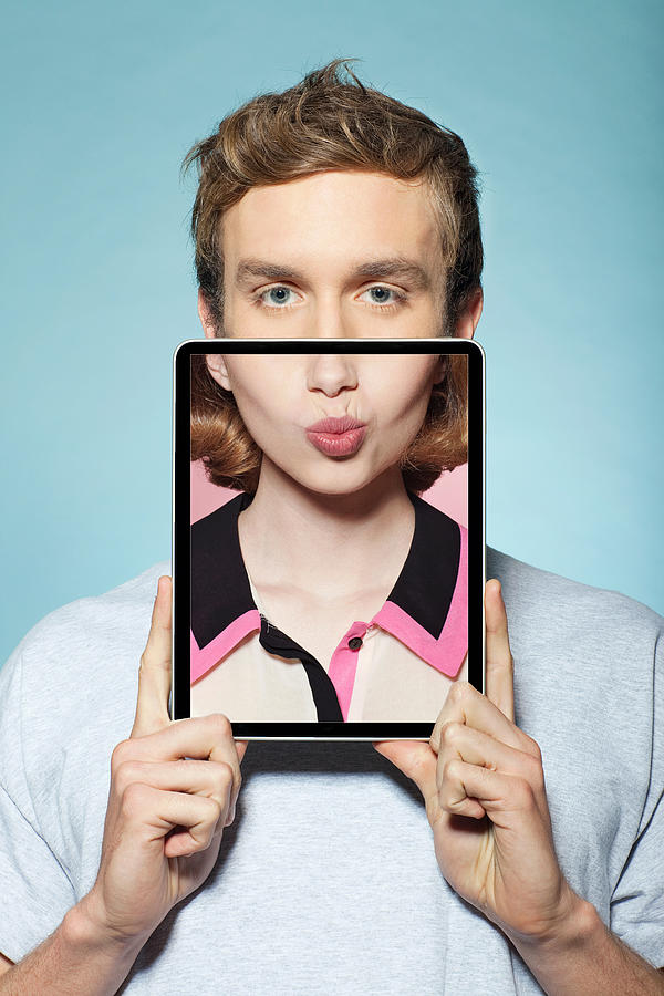 Man covering half his face with digital tablet, with womans mouth Photograph by Image Source