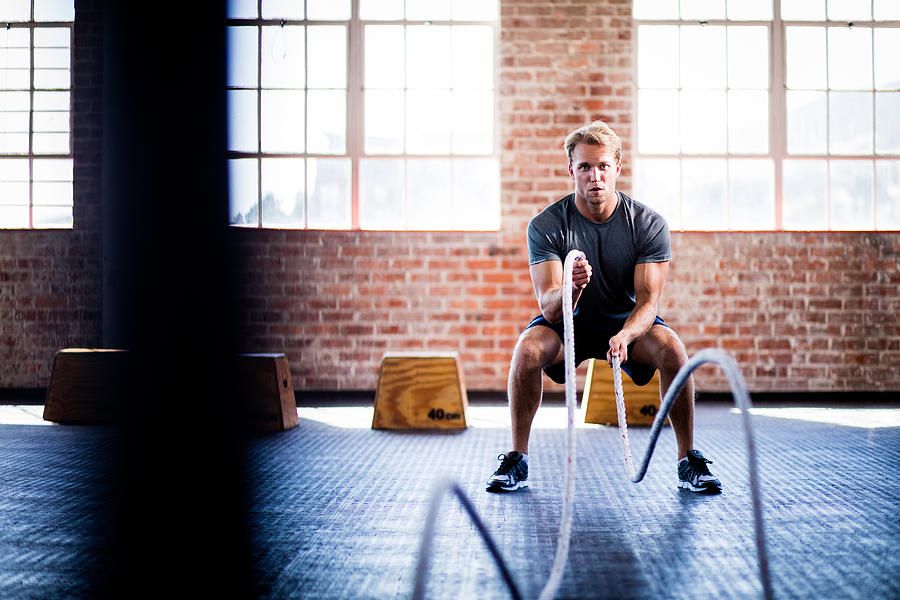 Man doing battle ropes exercise during gym training at gym Photograph by Wundervisuals