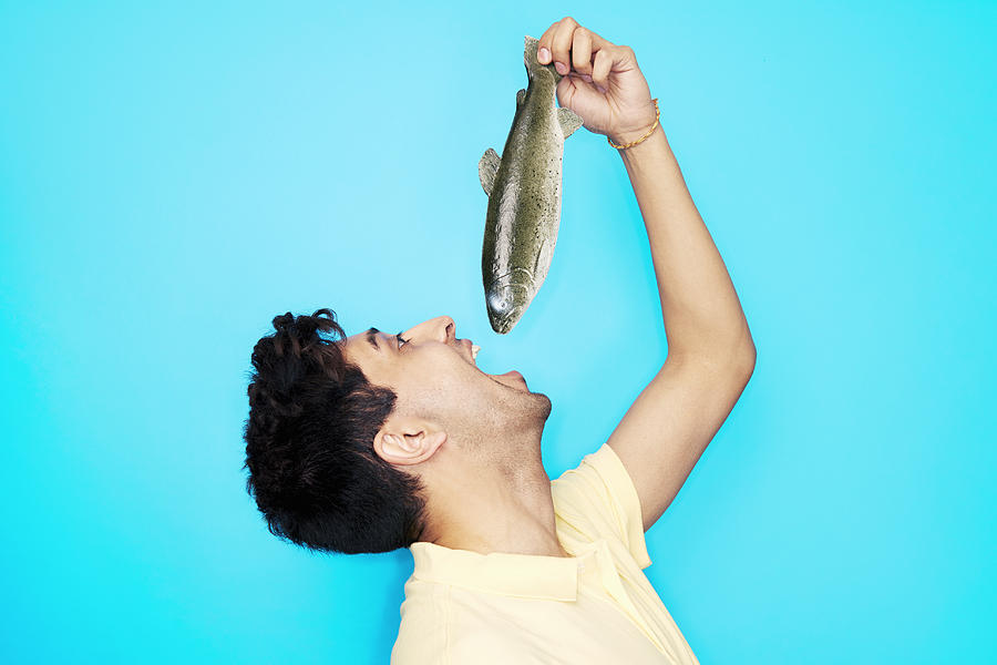 Man Eating Whole Fish Photograph by Tara Moore