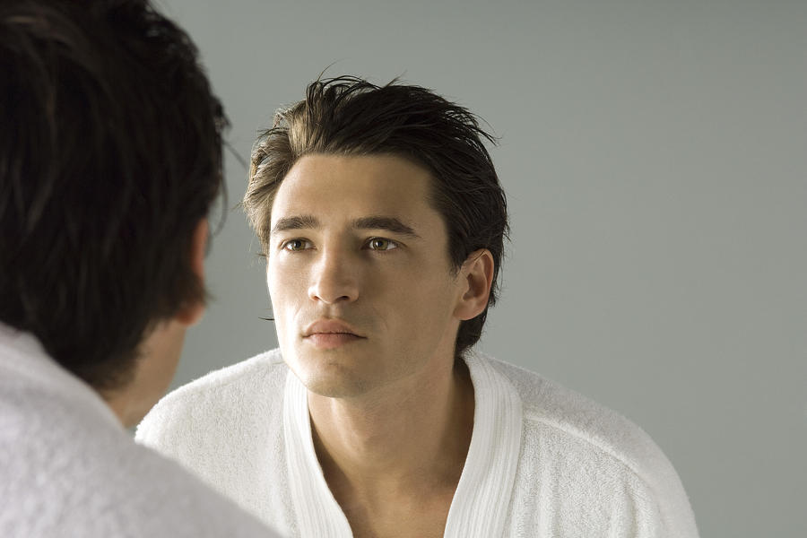 Man examining his face in the mirror, wearing bathrobe Photograph by PhotoAlto/Michele Constantini
