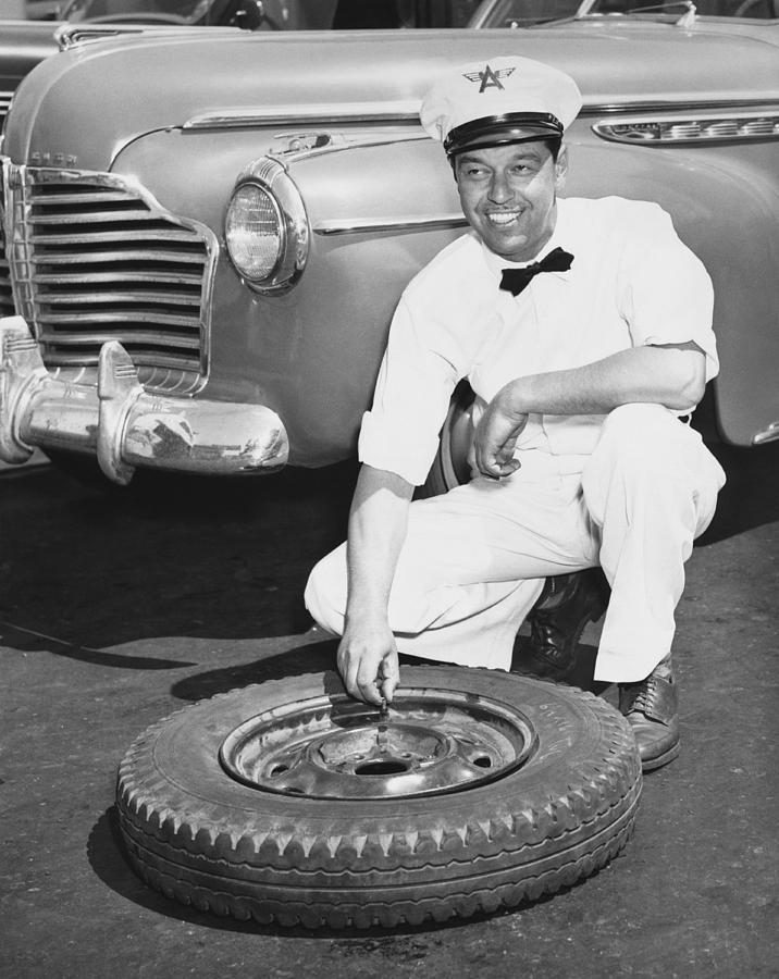 Man Fixing A Flat Tire Photograph by Underwood Archives