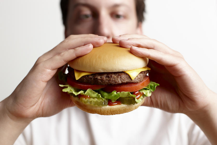 Man holding cheeseburger Photograph by Perch Images
