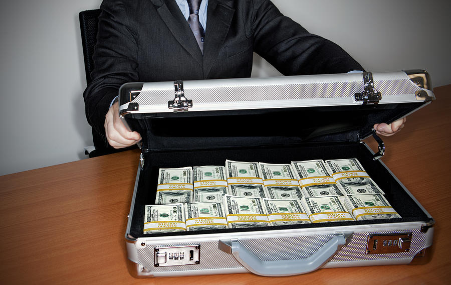 Man holding silver briefcase full of $100 bills Photograph by Caroline Purser
