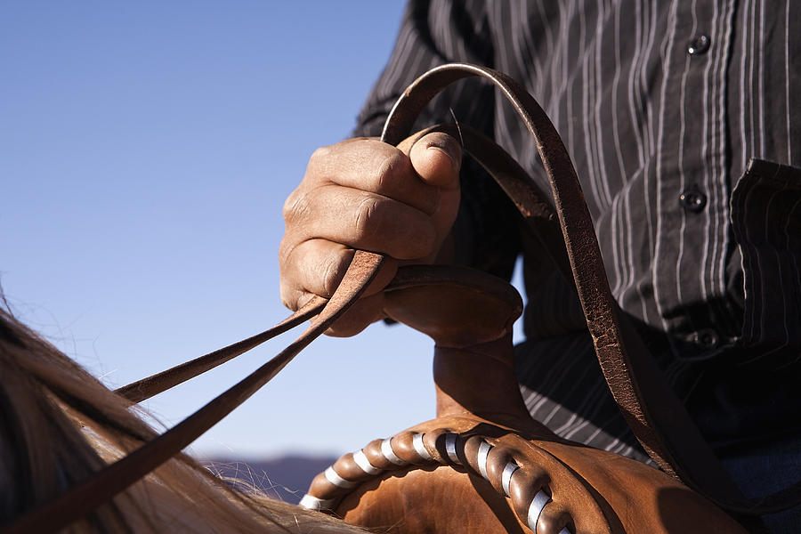 Man holding the reins of horse, close-up, focus on hand Photograph by Sean Russell
