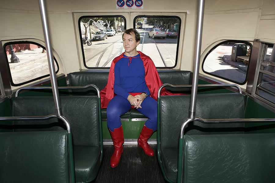 Man in superhero costume riding bus, hands clasped Photograph by Lauren Nicole