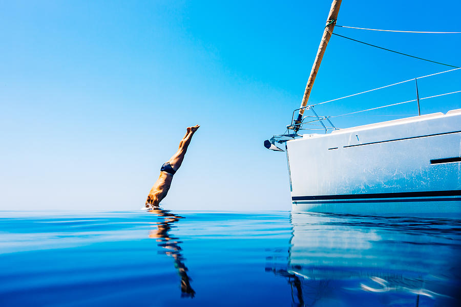 Man jumping in sea from sailboat Photograph by Mbbirdy