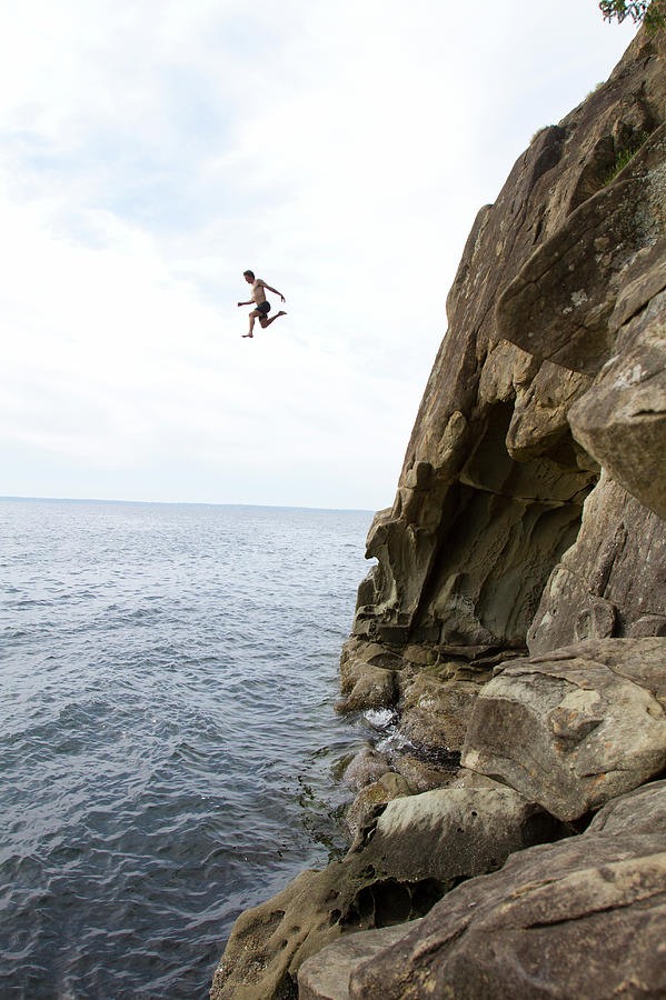 Person Jumping Off Cliff Into Water