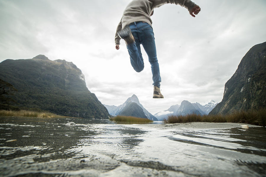 Man jumps over mountain river Photograph by Swissmediavision