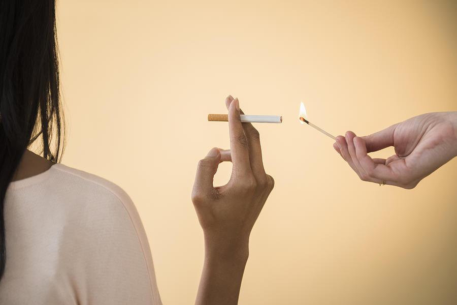 Man lighting womans cigarette Photograph by JGI/Jamie Grill