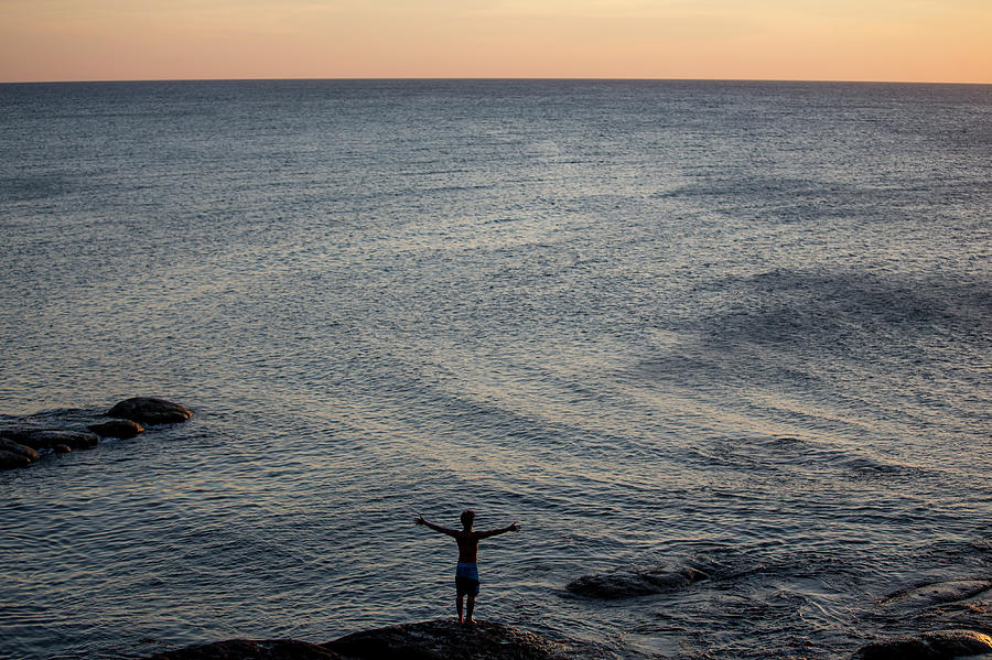 Man On Rock At Edge Of Sea With Arms Photograph by James Morgan