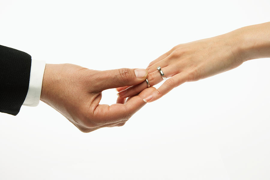 Man placing wedding band on womans hand (focus on hands) Photograph by Thomas Northcut