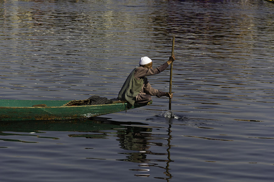 Man plying a wooden boat on the Dal Lake Photograph by Ashish Agarwal
