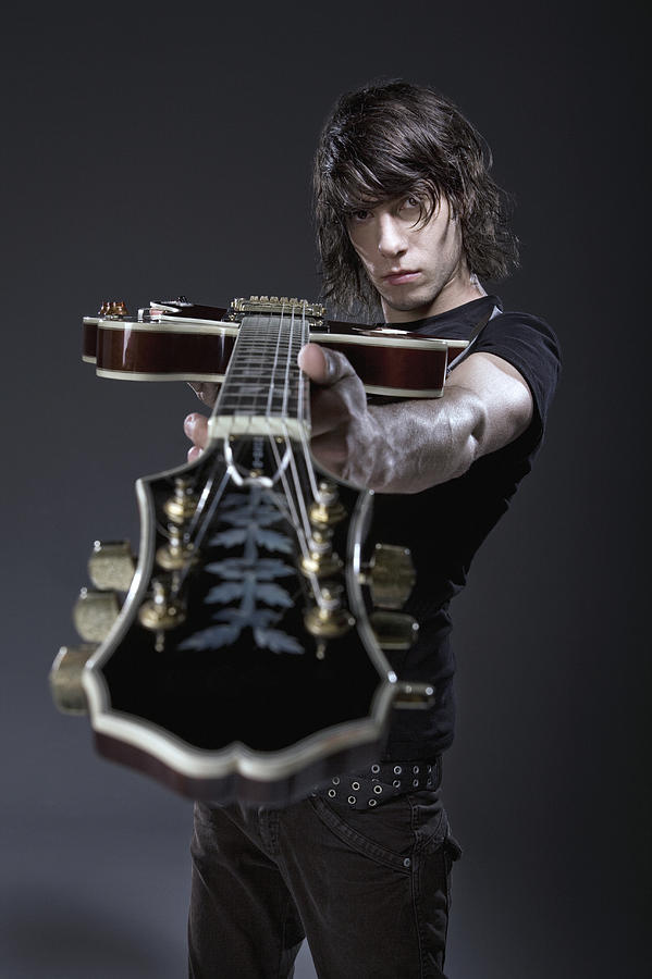 Man pointing electric guitar at camera Photograph by Simon Webb & Duncan Nicholls