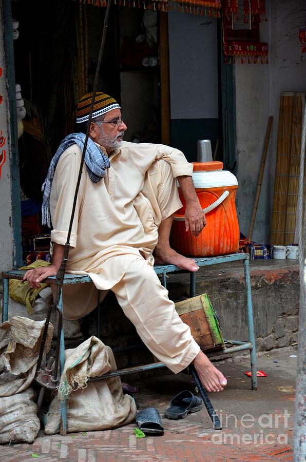 Man sits and relaxes in Lahore walled city Pakistan Photograph by Imran Ahmed