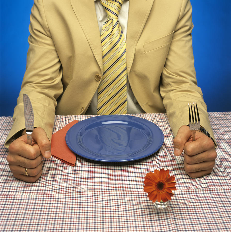 Man sitting at table with empty plate, holding cutlery Photograph by Jacob Lindner